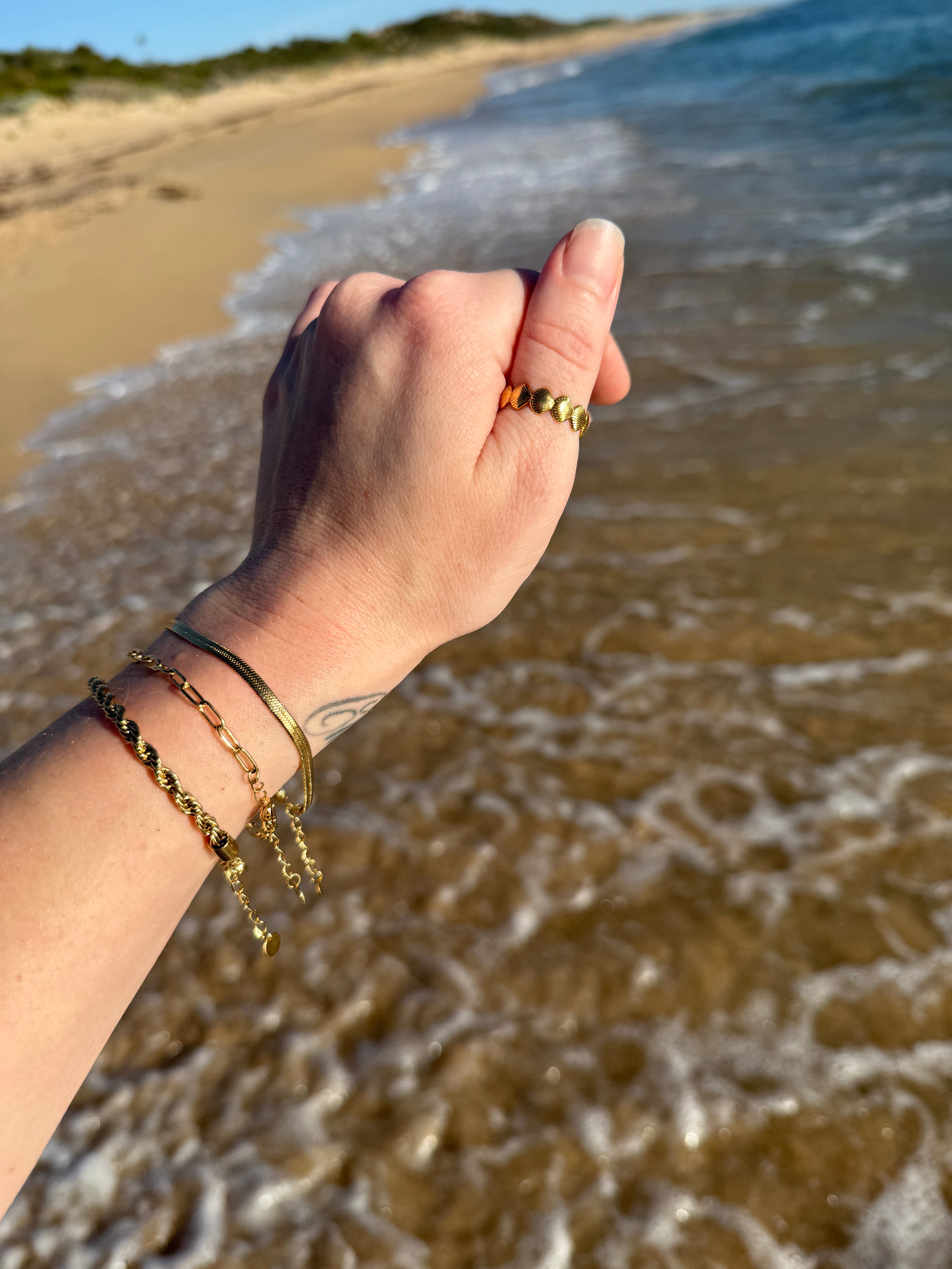 Waterproof 18k gold seashell ring featured on thumb at the beach 