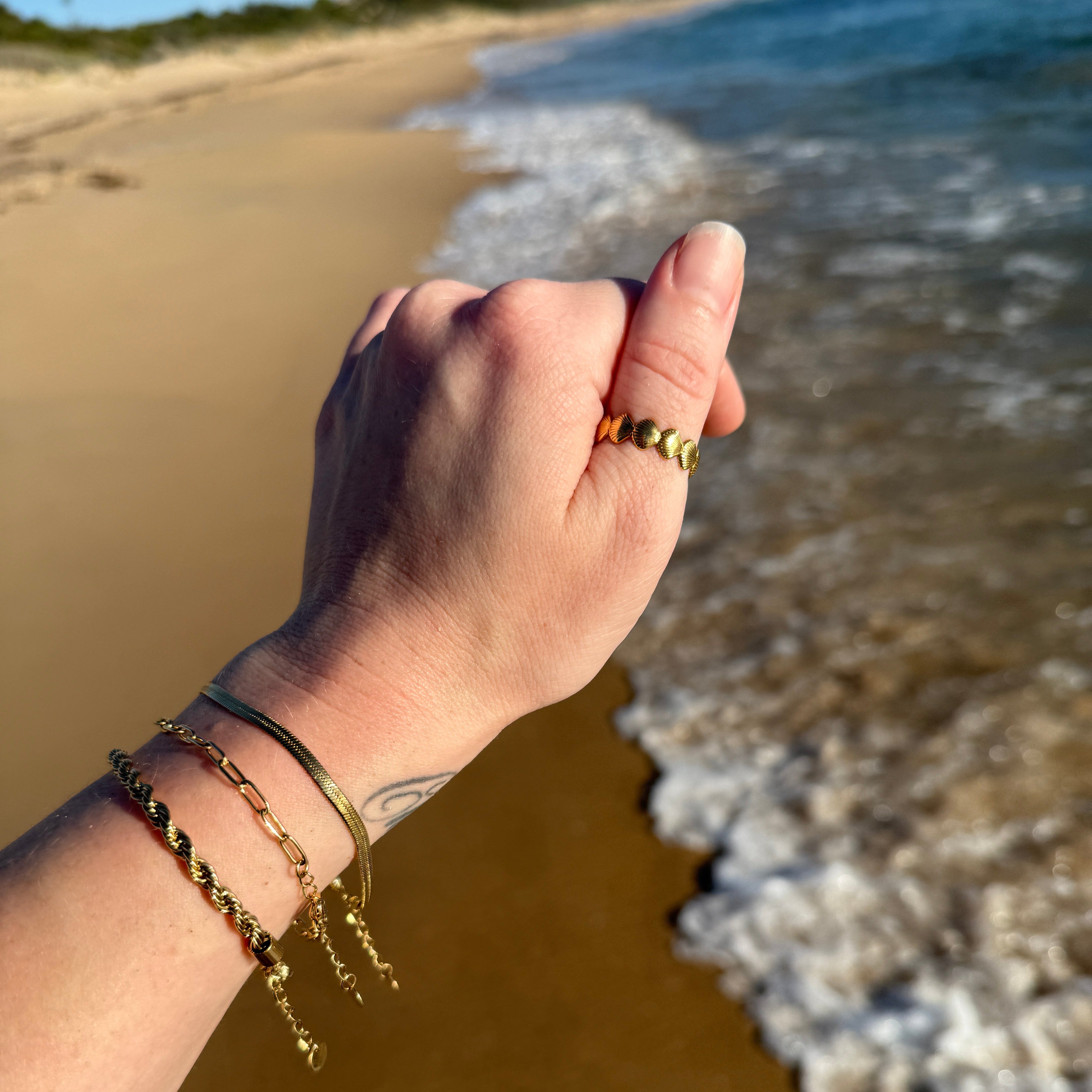 waterproof seashell ring on thumb at beach